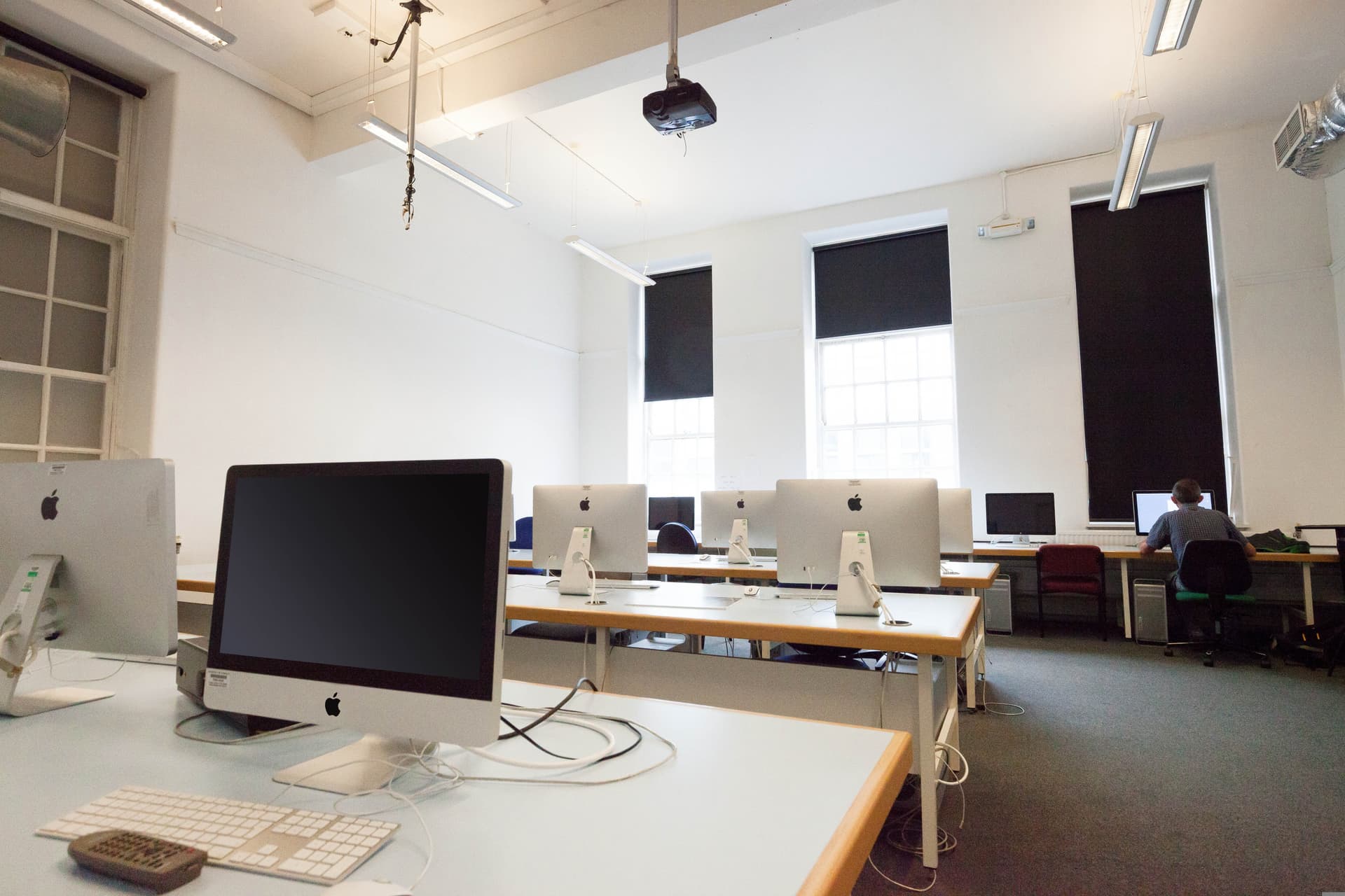 Salle avec plusieurs postes informatiques alignes et prets a etre utilises.
